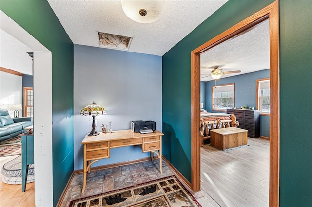 office featuring a textured ceiling, baseboards, ceiling fan, and wood finished floors