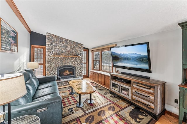 living area with baseboards, lofted ceiling, light wood-style flooring, a stone fireplace, and a textured ceiling