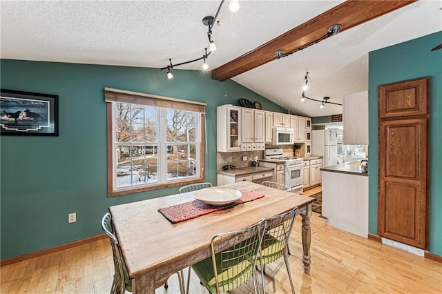 dining room featuring baseboards, light wood-style floors, vaulted ceiling with beams, and a textured ceiling