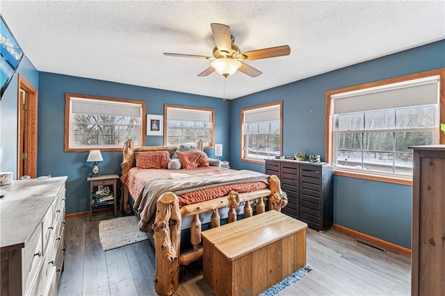 bedroom featuring light wood-type flooring, baseboards, visible vents, and ceiling fan