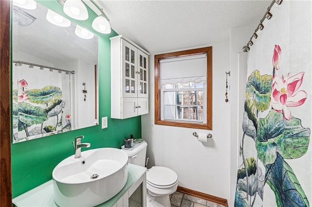 bathroom with baseboards, toilet, a shower with shower curtain, a textured ceiling, and vanity