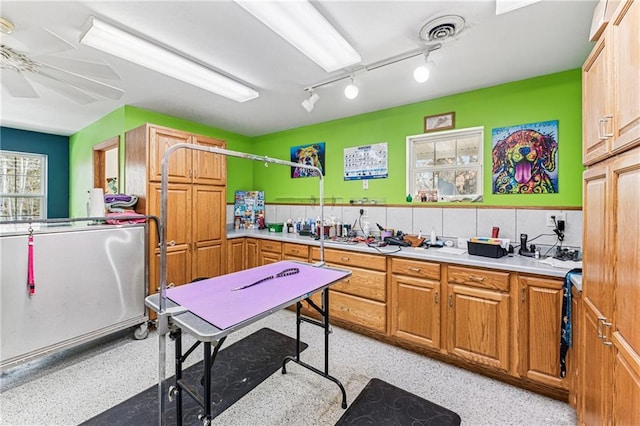 kitchen featuring visible vents, ceiling fan, light countertops, light speckled floor, and brown cabinets