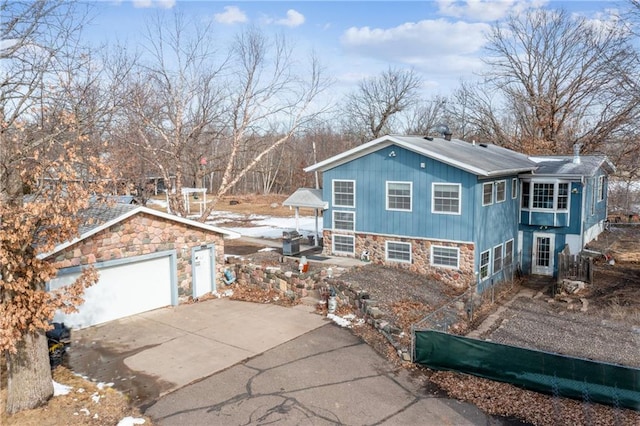 view of front of property with an outbuilding, a garage, stone siding, and driveway