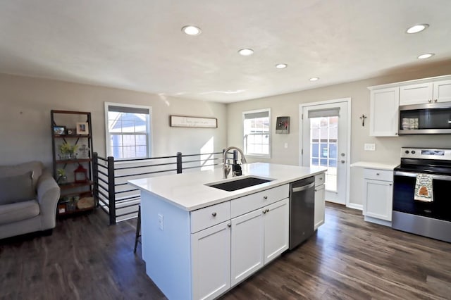 kitchen with a sink, stainless steel appliances, a center island with sink, and dark wood finished floors