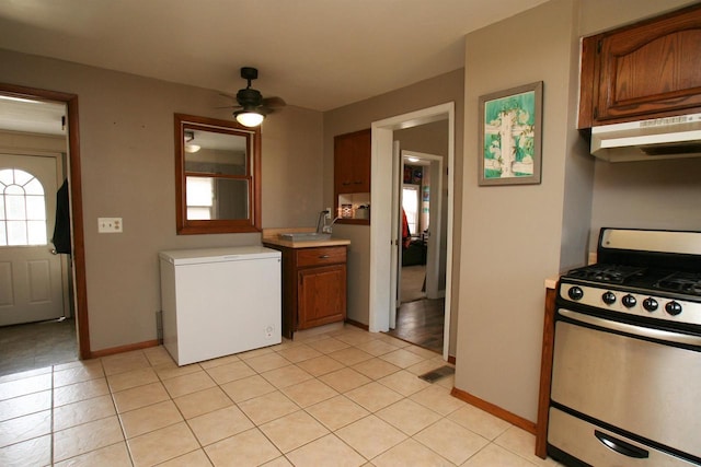 kitchen featuring gas stove, visible vents, refrigerator, light countertops, and under cabinet range hood