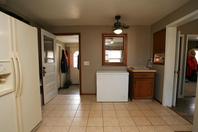 kitchen featuring a ceiling fan, light tile patterned flooring, light countertops, white refrigerator with ice dispenser, and fridge