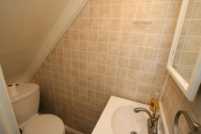 bathroom featuring tile walls, toilet, and a sink