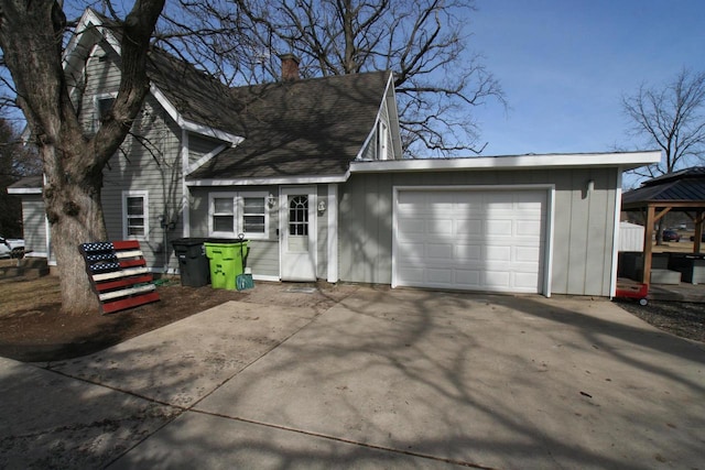 exterior space with a chimney, an attached garage, and concrete driveway