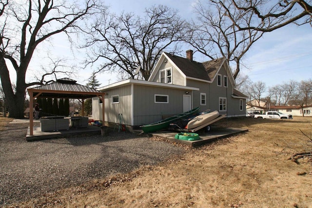 rear view of property featuring a gazebo and a chimney