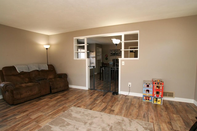 living room featuring wood finished floors, visible vents, and baseboards