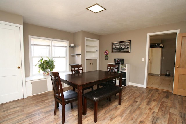 dining area with built in features, light wood-type flooring, and baseboards