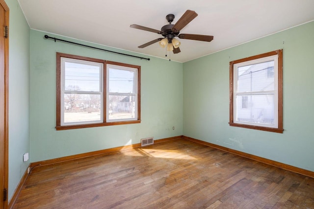 spare room with visible vents, plenty of natural light, baseboards, and wood-type flooring