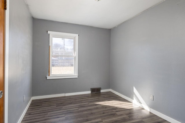 unfurnished room featuring visible vents, baseboards, and dark wood-style floors