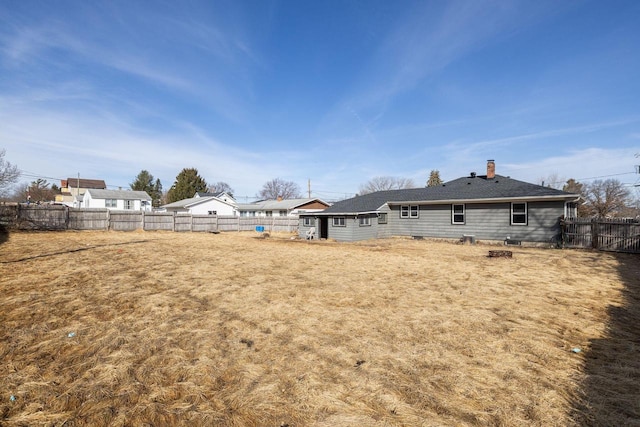 rear view of house with a fenced backyard and a chimney