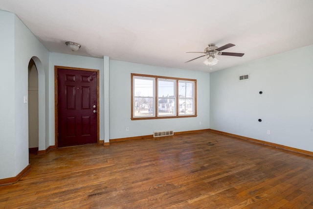 interior space featuring arched walkways, visible vents, baseboards, and wood finished floors