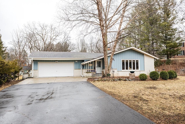 view of front of home featuring brick siding, a chimney, aphalt driveway, and a garage