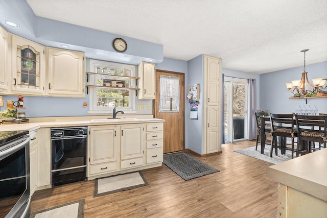 kitchen with pendant lighting, a sink, light wood-style floors, stainless steel electric range, and light countertops