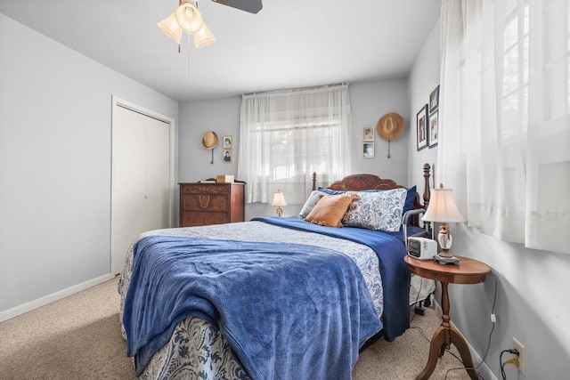 carpeted bedroom with a closet, baseboards, and ceiling fan