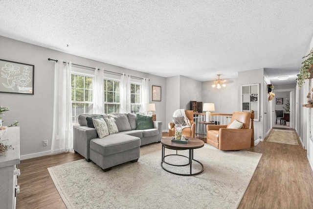 living room featuring baseboards, a textured ceiling, and wood finished floors