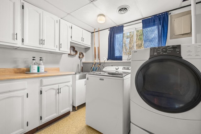 clothes washing area featuring separate washer and dryer, visible vents, and a sink