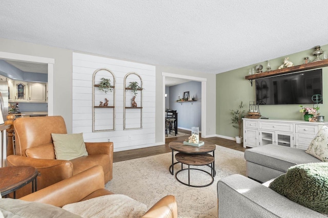 living room with a textured ceiling, baseboards, and wood finished floors