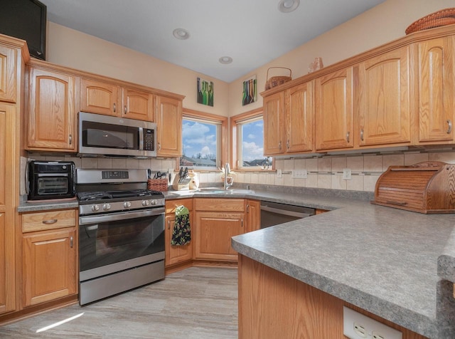 kitchen with a sink, backsplash, recessed lighting, stainless steel appliances, and light wood-style floors