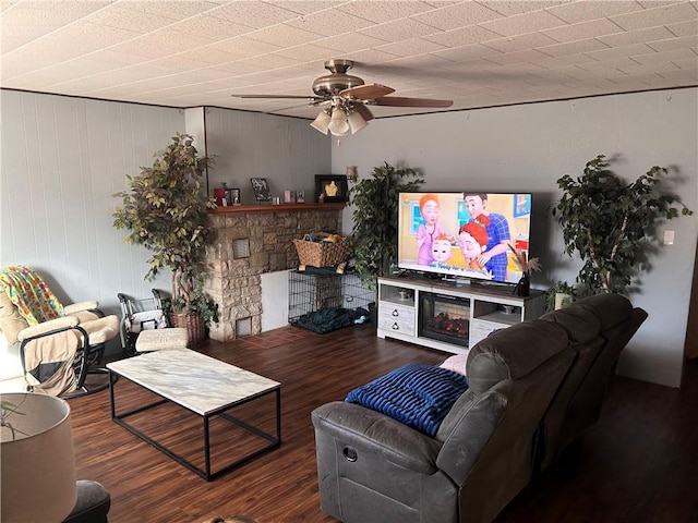 living area featuring a stone fireplace, wood finished floors, and a ceiling fan