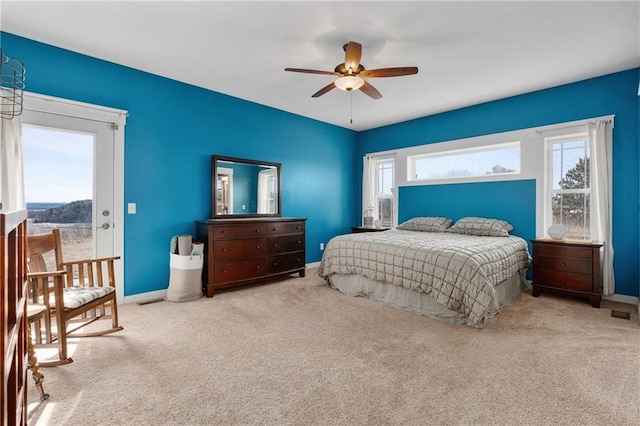 carpeted bedroom featuring multiple windows, a ceiling fan, and baseboards