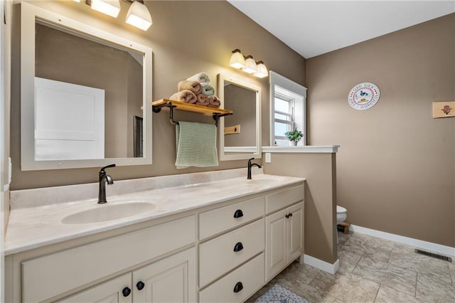 full bathroom with a sink, baseboards, toilet, and double vanity