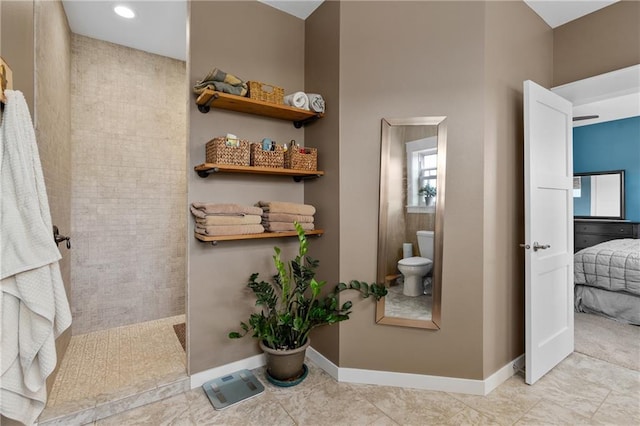 ensuite bathroom with connected bathroom, walk in shower, toilet, and baseboards