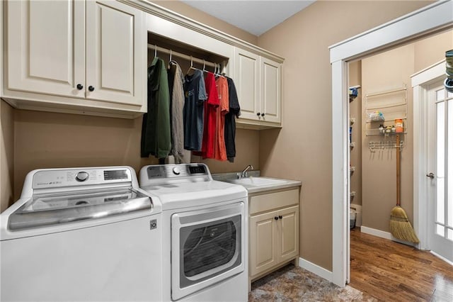 clothes washing area featuring washer and dryer, baseboards, cabinet space, and a sink