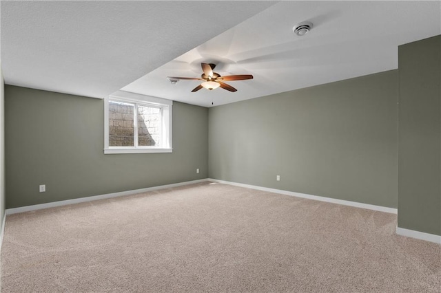 empty room featuring a ceiling fan, light colored carpet, and baseboards