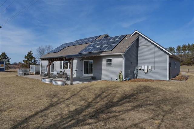 back of property with a patio area, a lawn, and roof mounted solar panels