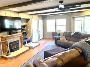 living room featuring ceiling fan, wood finished floors, beam ceiling, and a fireplace with raised hearth