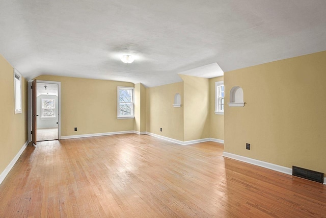 unfurnished living room featuring visible vents, lofted ceiling, light wood-type flooring, and baseboards