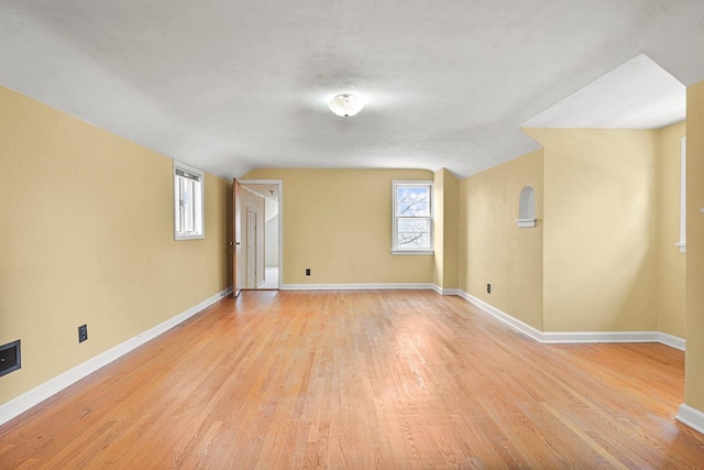 unfurnished room featuring light wood-style flooring, baseboards, and lofted ceiling