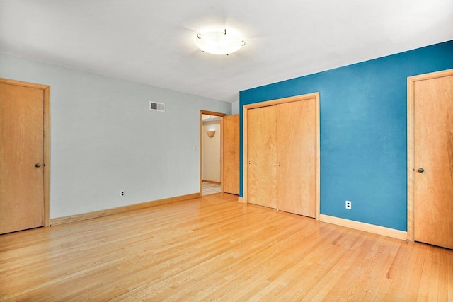 unfurnished bedroom featuring visible vents, baseboards, and wood finished floors