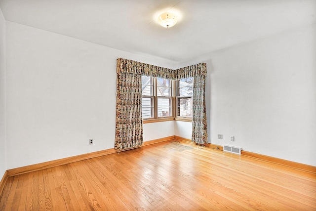 spare room with visible vents, baseboards, and wood finished floors