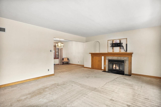 unfurnished living room featuring an inviting chandelier, carpet, baseboards, and a premium fireplace