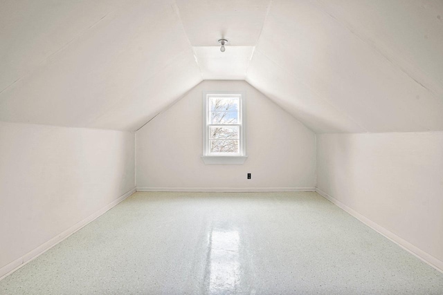 additional living space featuring baseboards and vaulted ceiling