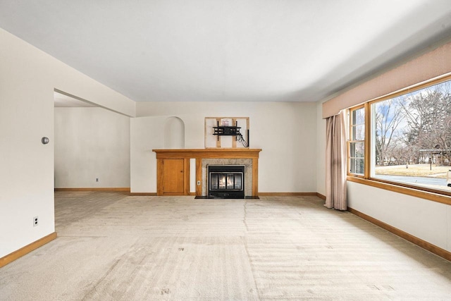 unfurnished living room with a fireplace with flush hearth, baseboards, and light carpet