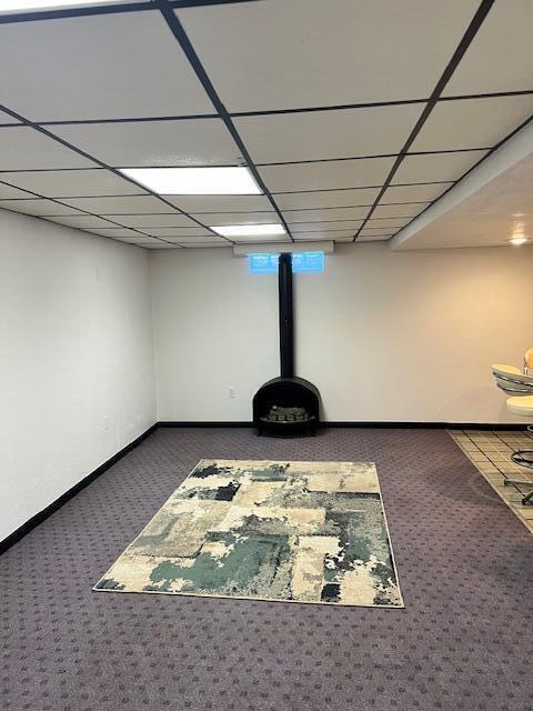 interior space featuring a drop ceiling, baseboards, and carpet floors