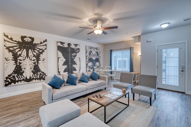 living area with visible vents, a ceiling fan, baseboards, and wood finished floors