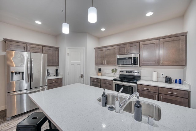 kitchen with a sink, dark brown cabinetry, pendant lighting, and stainless steel appliances