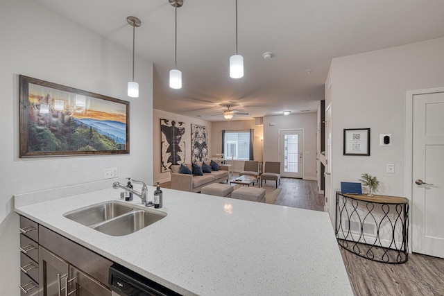 kitchen featuring light stone counters, wood finished floors, ceiling fan, a sink, and decorative light fixtures