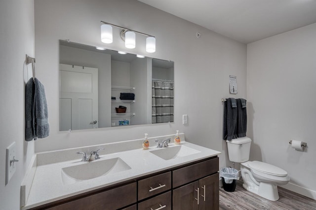 full bathroom featuring double vanity, toilet, wood finished floors, and a sink