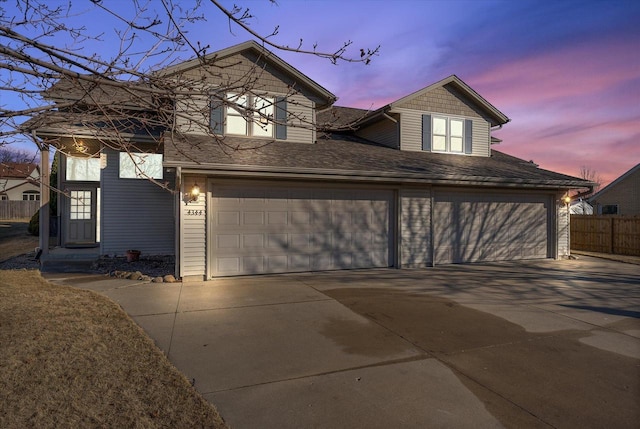 view of front of home featuring concrete driveway, an attached garage, and fence