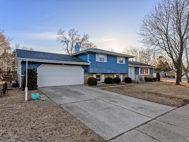 split level home featuring a garage, driveway, a chimney, and a shingled roof