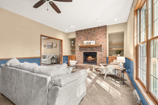 living room with built in features, visible vents, a fireplace, a textured ceiling, and carpet flooring