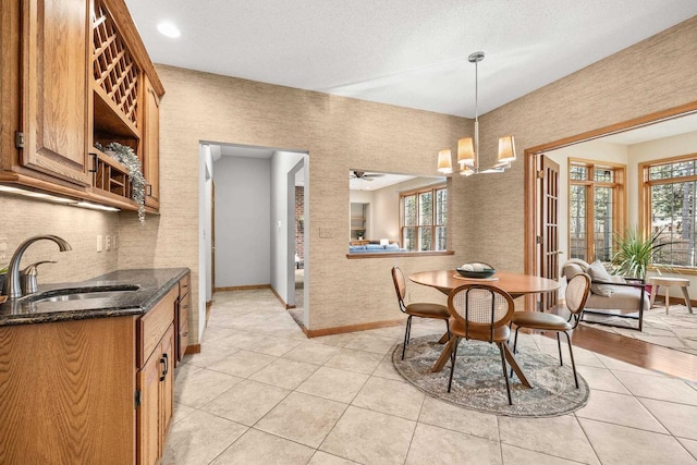 dining room featuring light tile patterned floors, ceiling fan with notable chandelier, a textured ceiling, and baseboards